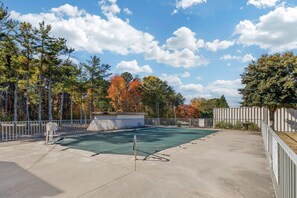An outdoor tennis court with a metal fence, trees with autumn foliage, and a clear sky. - Quality Inn & Suites Easley - Greenville (Easley)