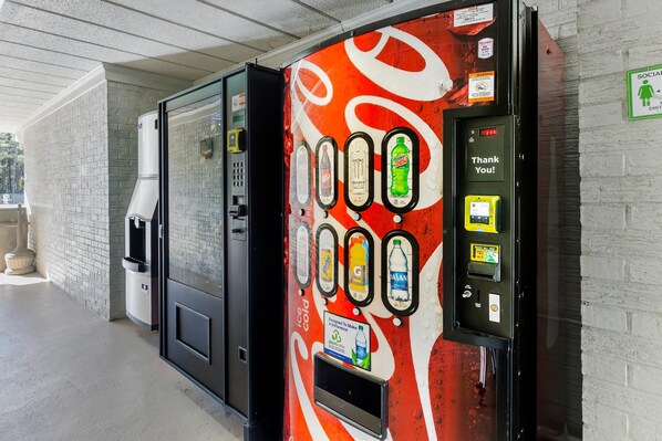 Una máquina expendedora con diseño de Coca-Cola, un dispensador de agua y un letrero que dice