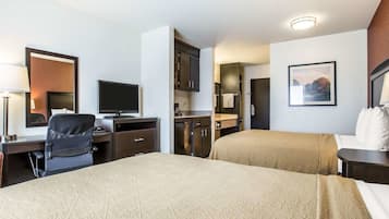 Una habitación de hotel con cama, escritorio con computadora, televisión, baño y un cuadro en la pared.