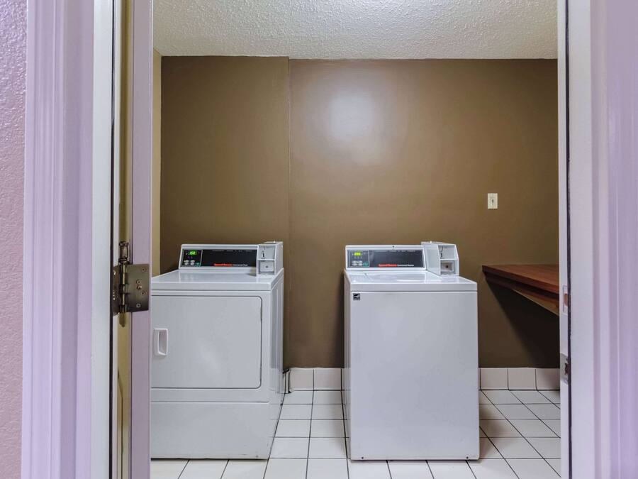 Un cuarto de lavandería con dos lavadoras de carga frontal y un mostrador de madera.