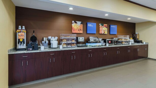A breakfast bar with coffee machines, a waffle maker, and a microwave. - Comfort Inn Randolph - Boston (Randolph)