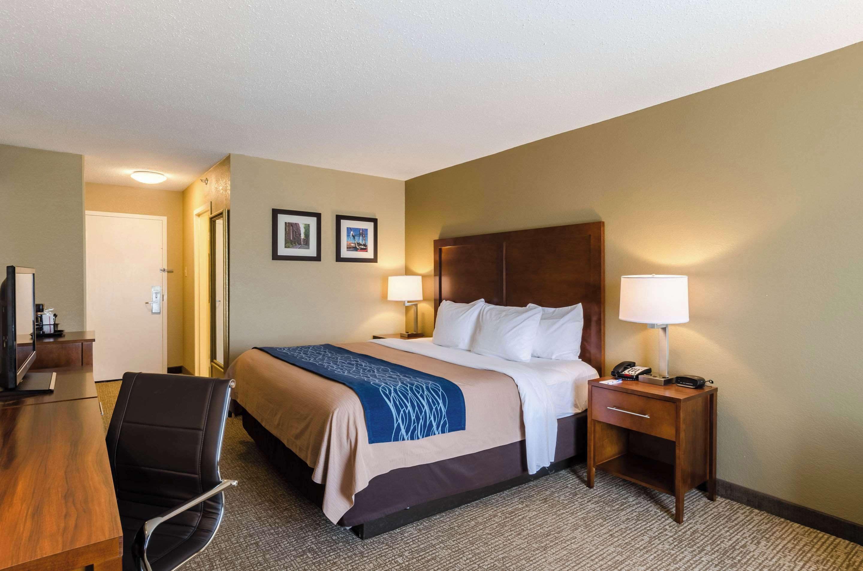 A hotel room with a bed, bedside tables, a desk, and a chair.