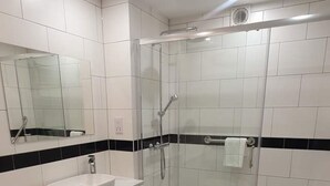 Ein modernes Badezimmer mit einer begehbaren Glasdusche, einem weißen Waschbecken und einer Toilette.