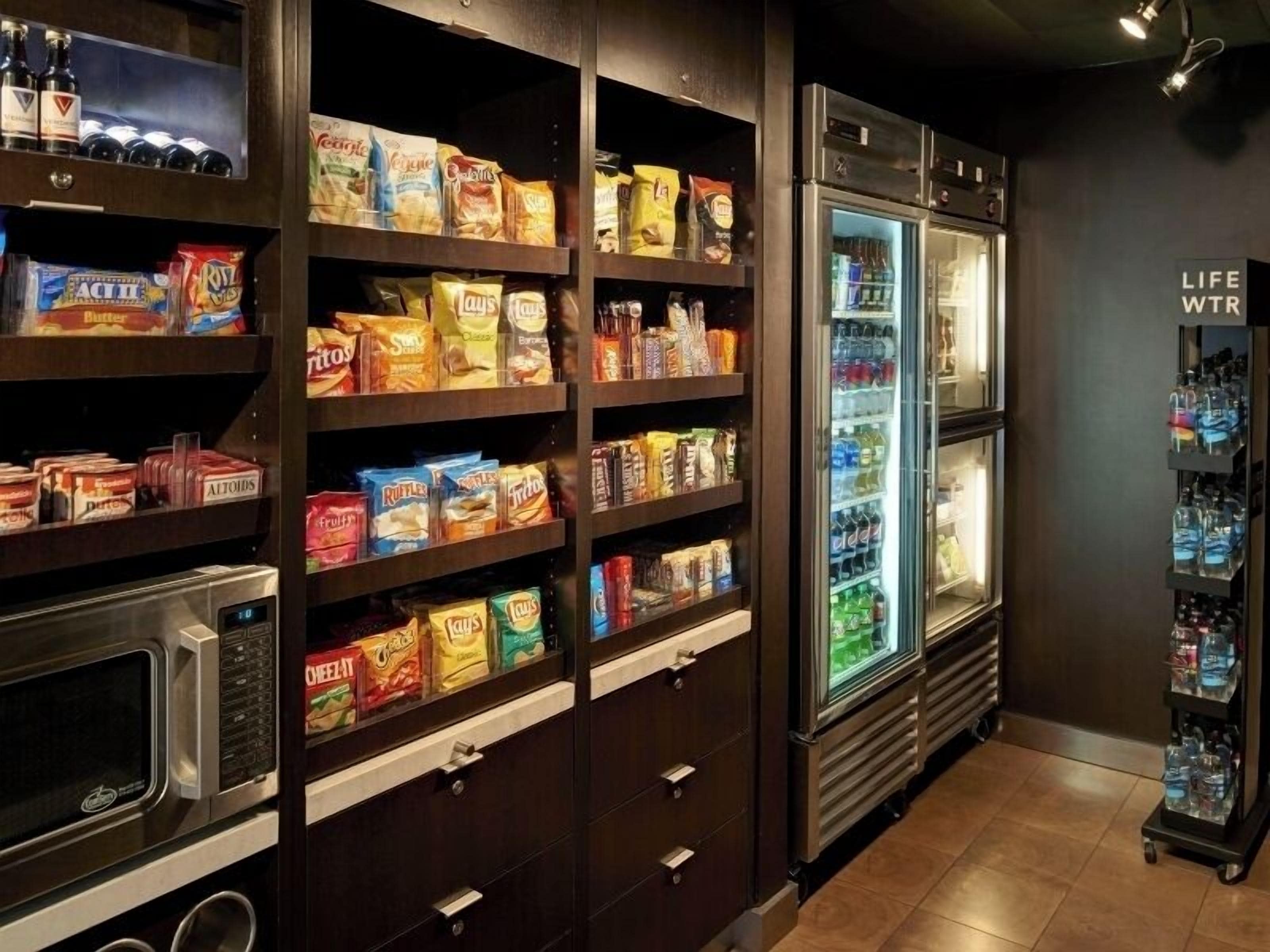 Un bar de aperitivos con estantes llenos de diferentes productos y un mostrador refrigerado.