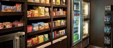 En snackbar med hylder fyldt med forskelligt snacks og et køleskab med madvarer.