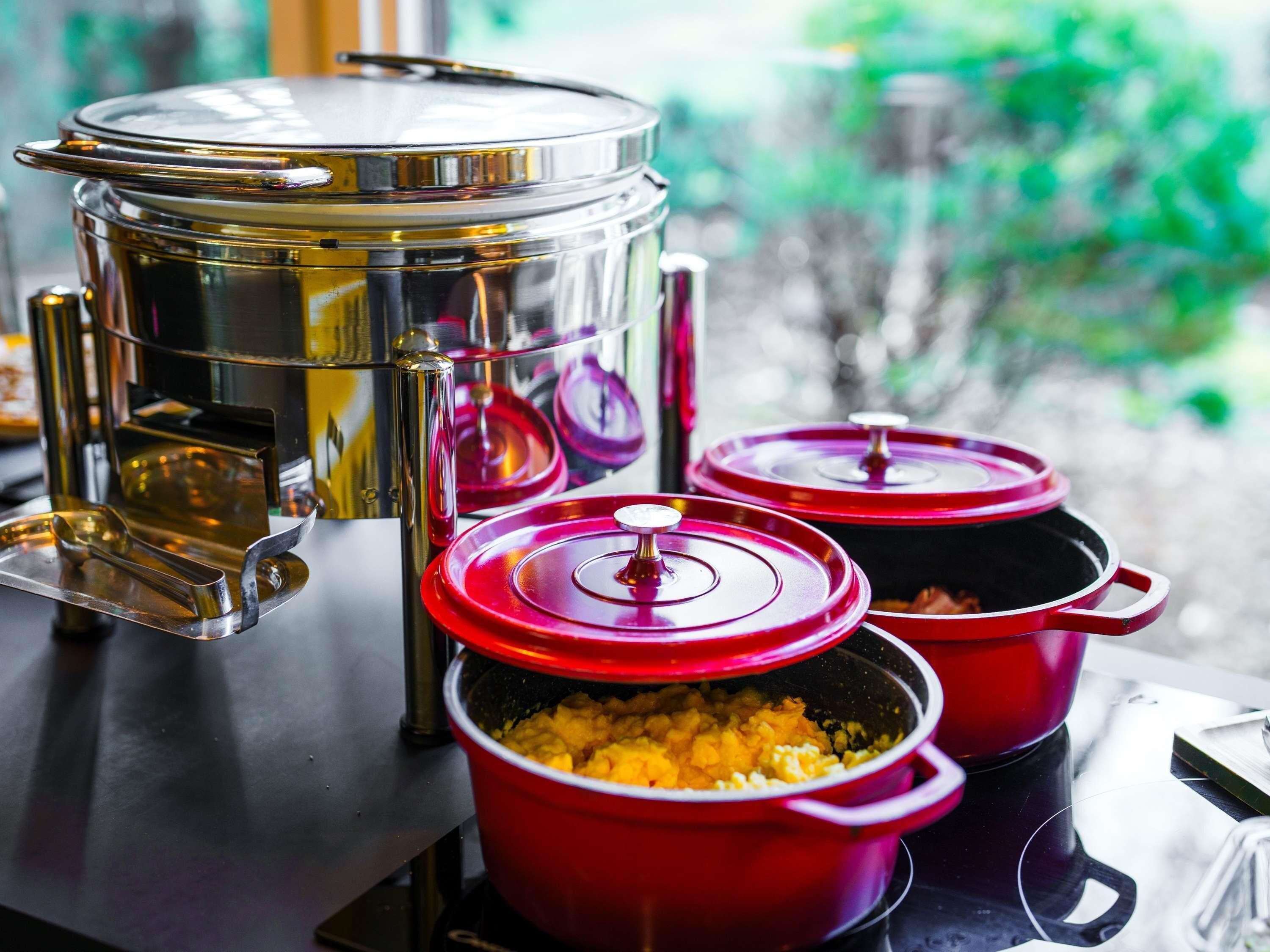 Una cocina con electrodomésticos de acero inoxidable y ollas rojas sobre una encimera.