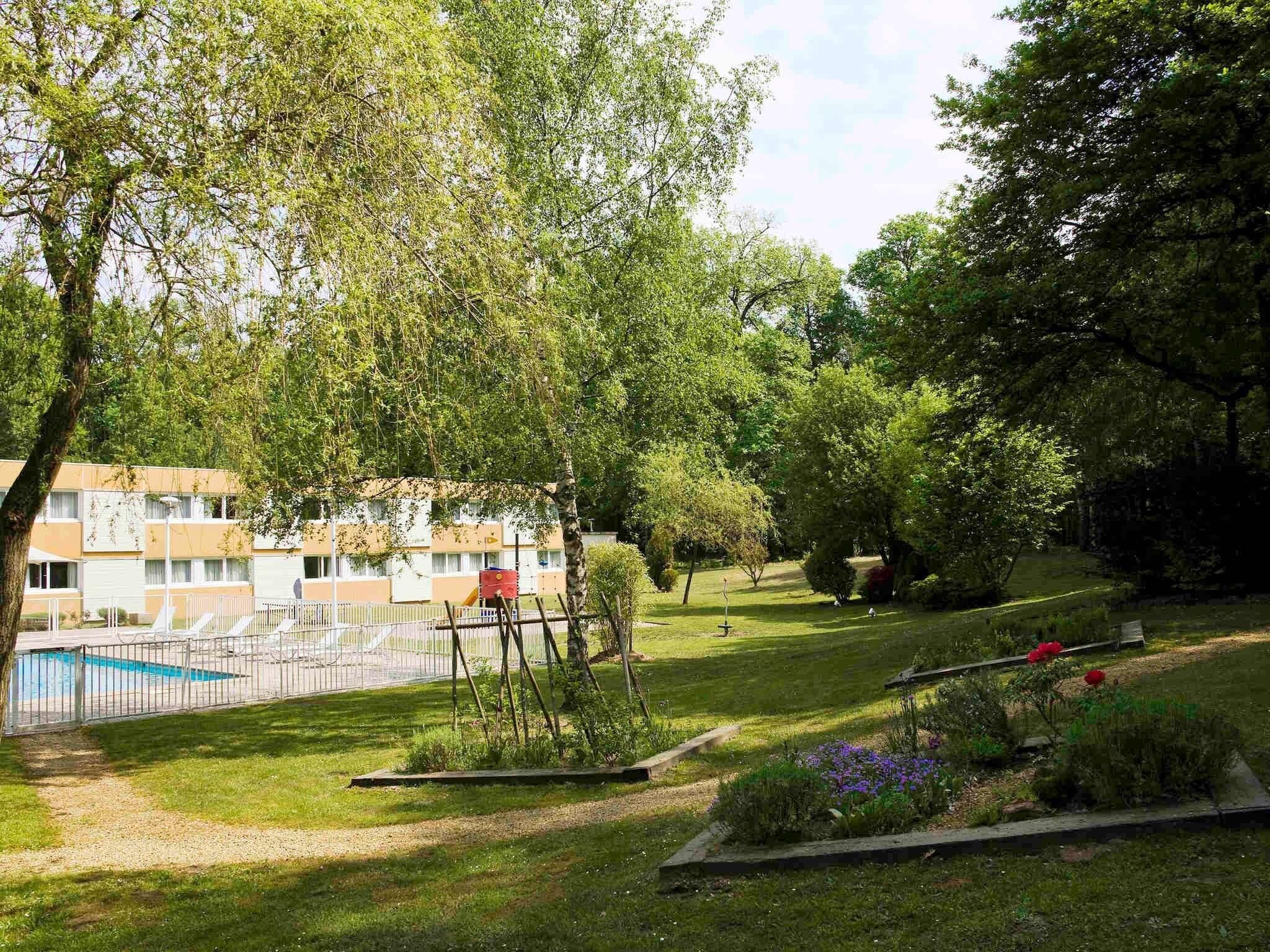 Un quartiere residenziale con piscina, area giochi e prato curato.