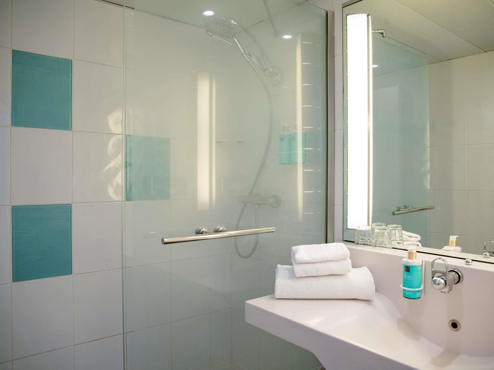 A modern bathroom with a glass shower enclosure, a white sink, and a mirror.