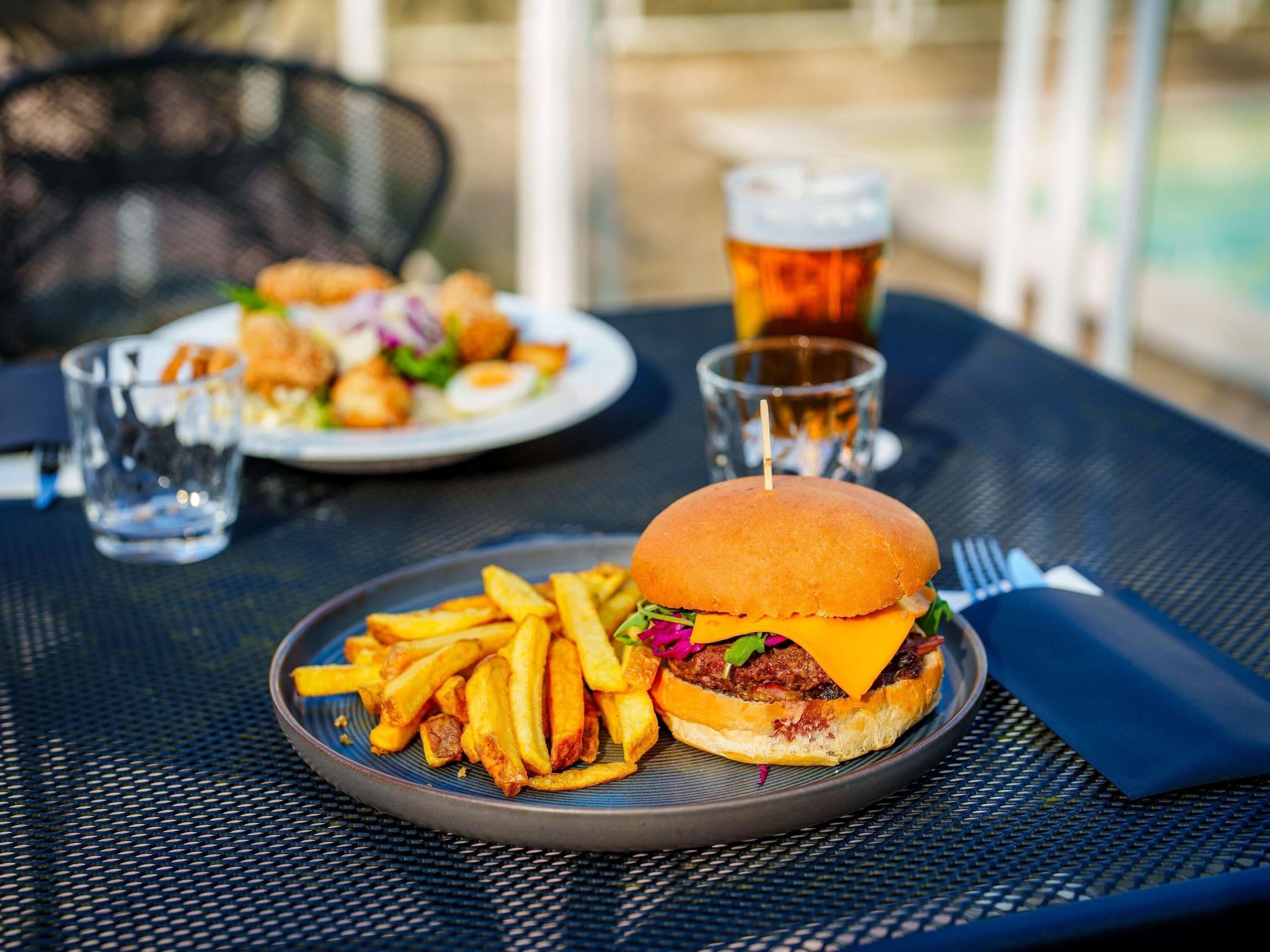 Un repas composé d’un hamburger, de frites et d’une boisson, servi sur une table.