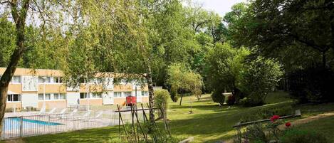 Un quartier résidentiel doté d’une piscine, d’un jardin clôturé et d’un immeuble avec de nombreuses fenêtres.