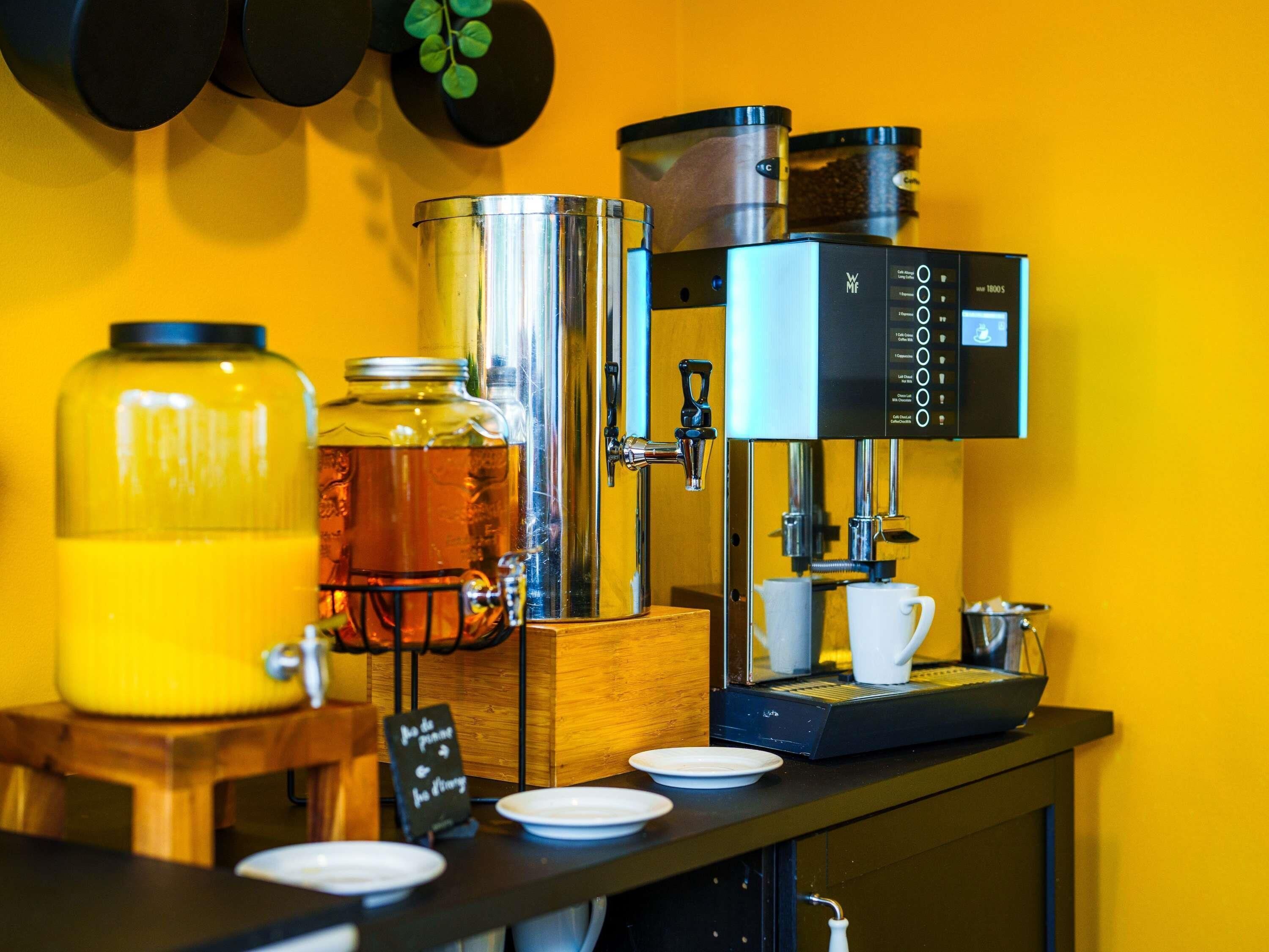 Un racó de cafè amb una màquina de cafè, un got gran de te i una cafetera.