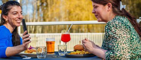 Zwei Personen essen an einem Tisch im Freien mit Blick auf einen Pool.