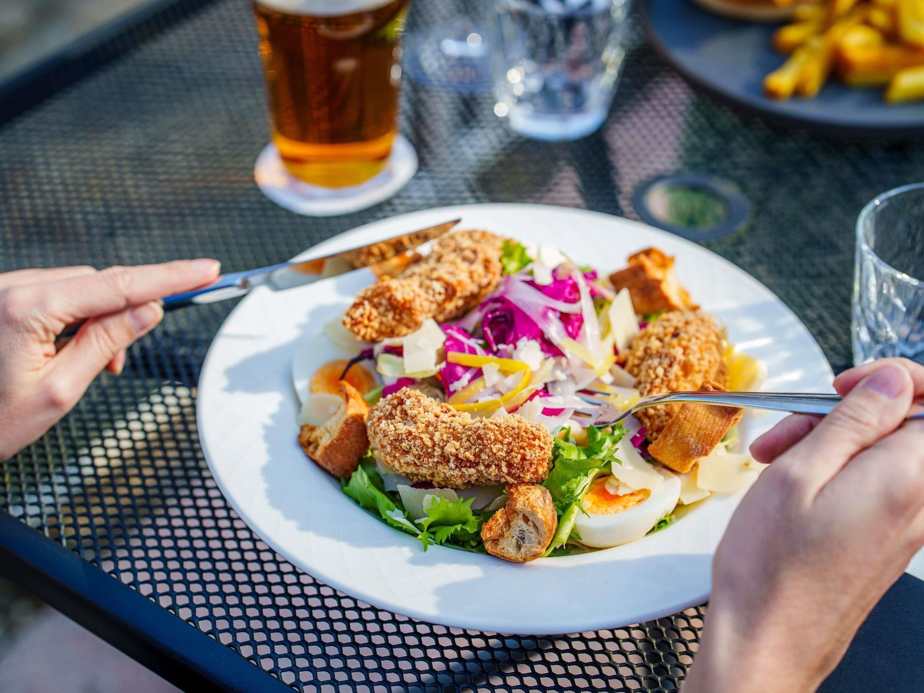 Un plato con pollo empanizado, ensalada y una bebida sobre una mesa.