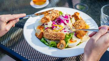 Un plato con pollo empanizado, ensalada y una bebida sobre una mesa.