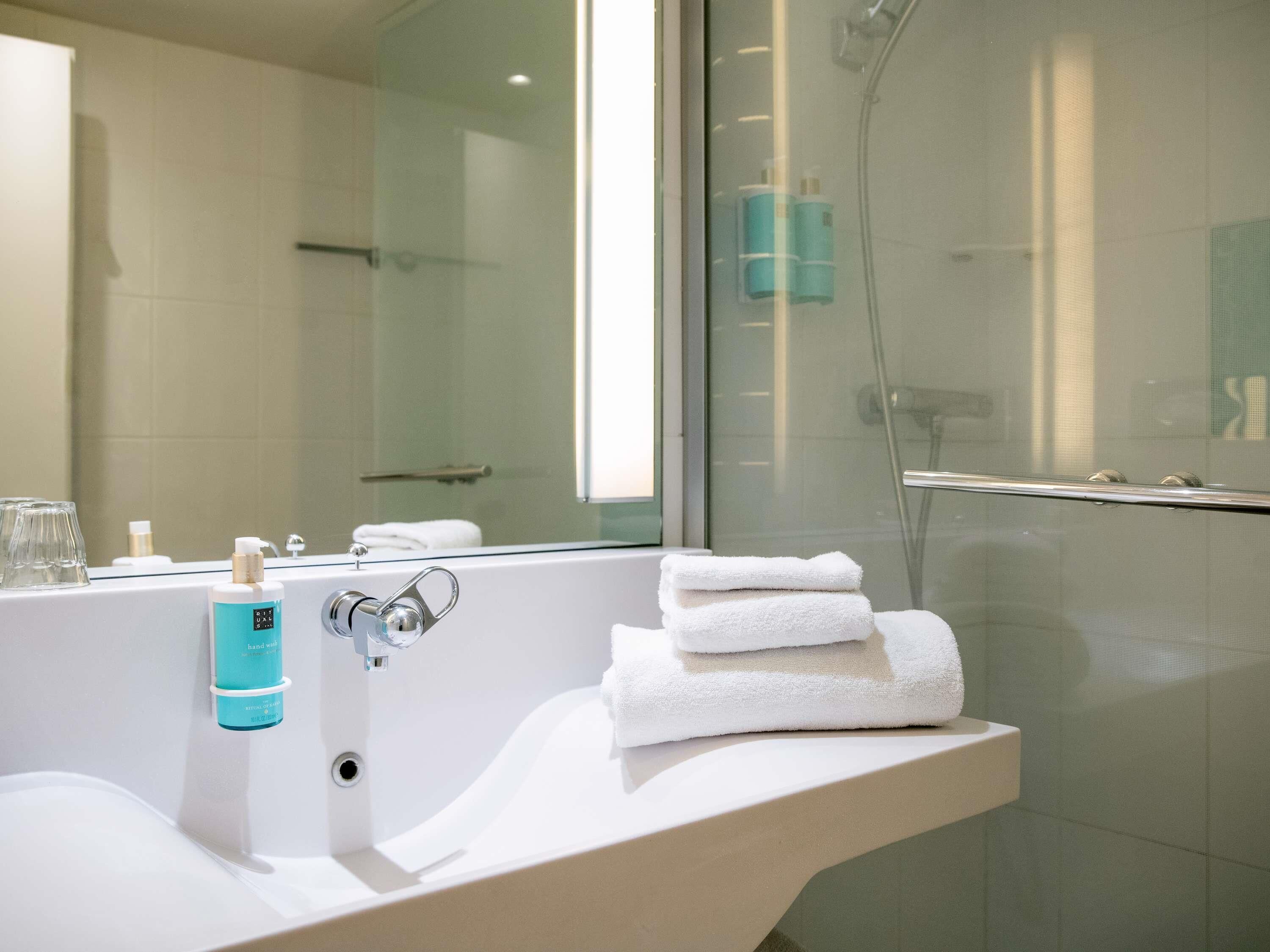 A modern bathroom with a large bathtub, a glass shower enclosure, and a sink with a towel stack.