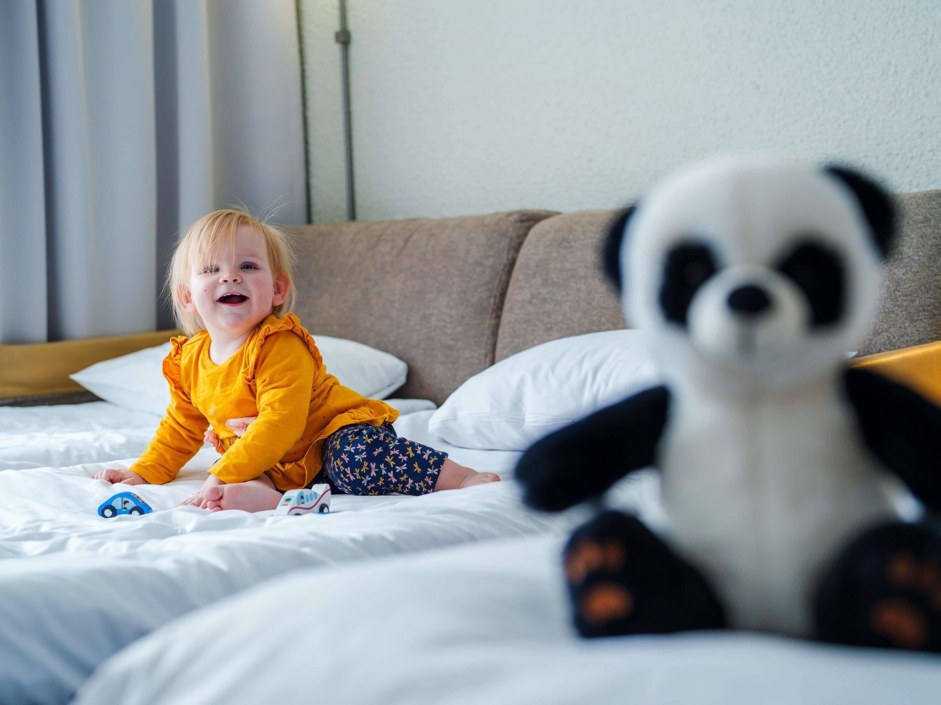 Un niño en una cama con un peluche de panda.
