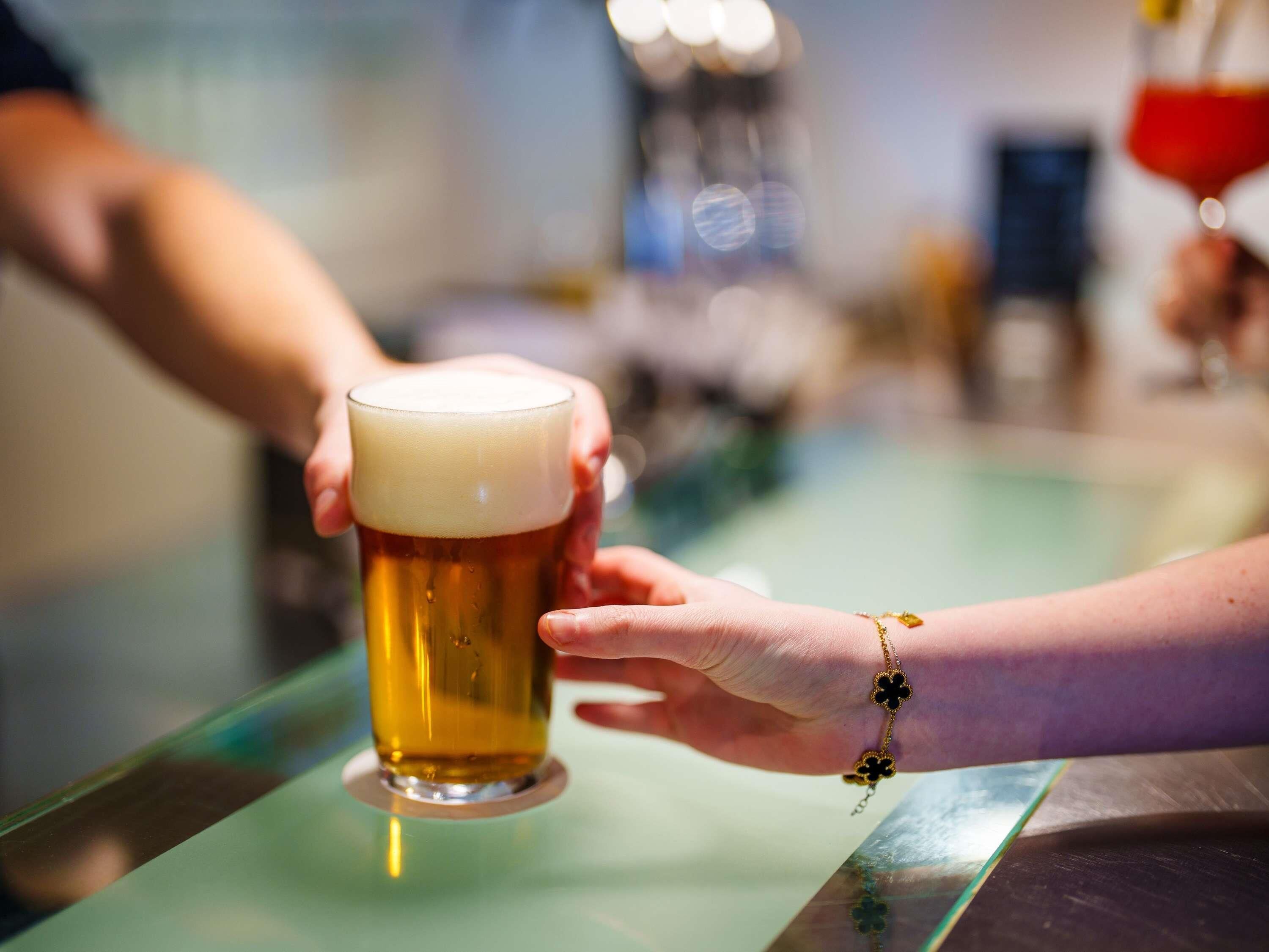 Una persona sosteniendo una cerveza en un bar.
