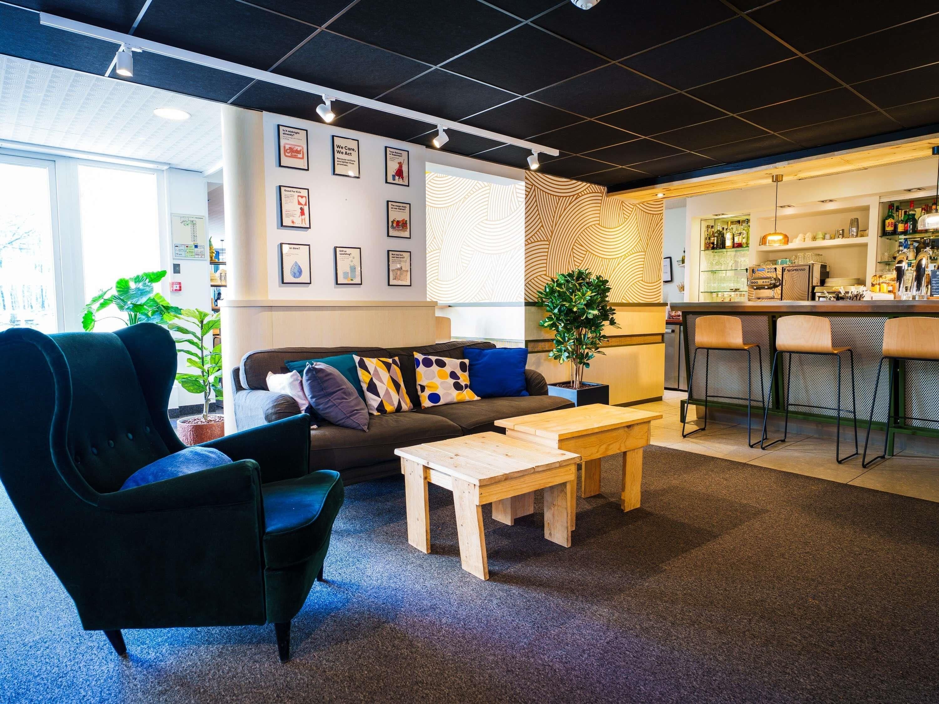A modern lounge area with a sofa, armchairs, a coffee table, and a bar with stools.