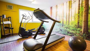 Een sportschool met trainingsapparatuur, een yogamat en een grote fitnessbal.