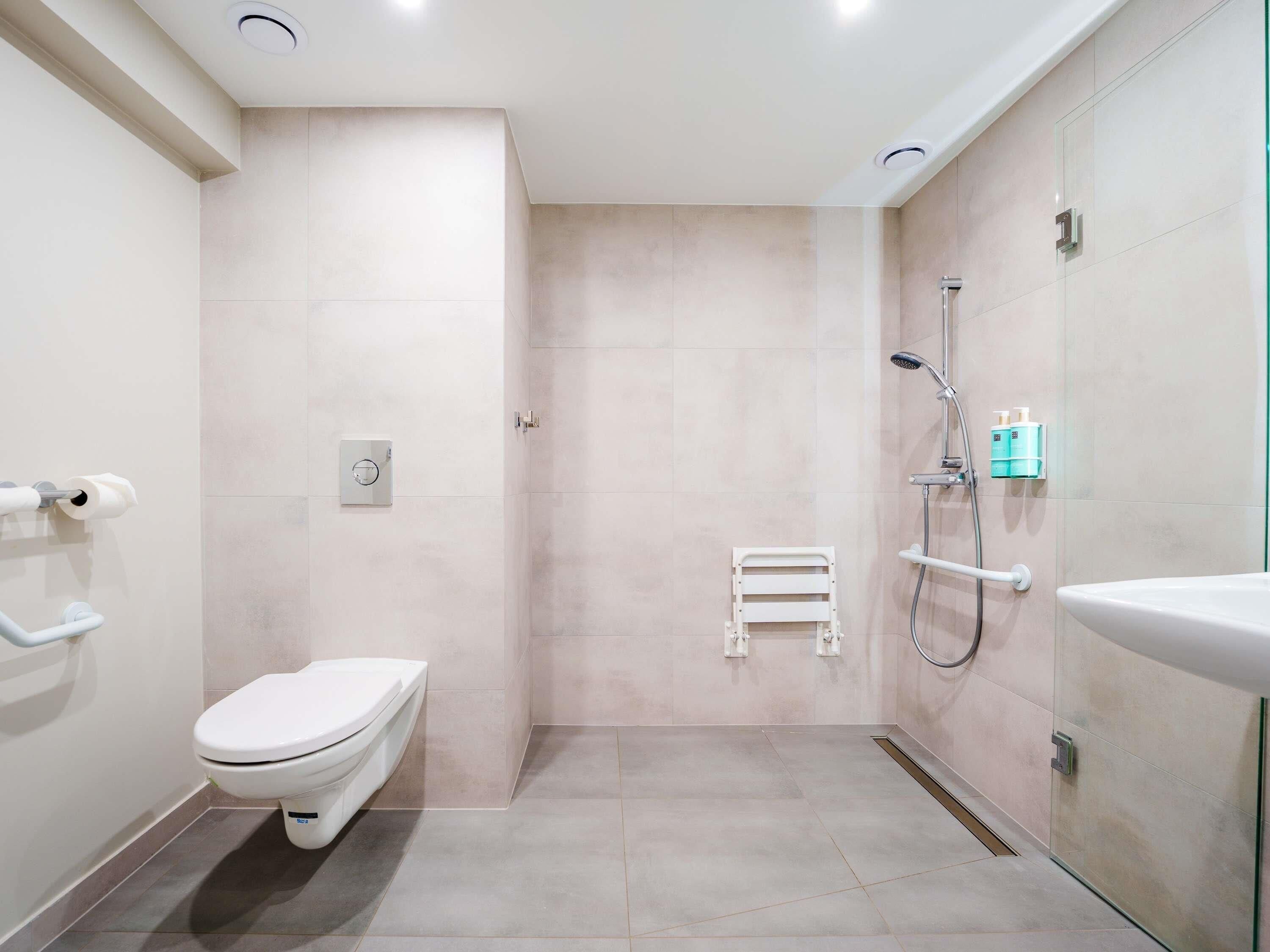 A modern bathroom with a toilet, a shower area, and a sink.