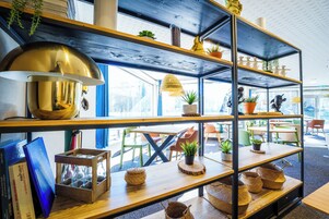 A modern interior with wooden shelves, potted plants, and a large brass lamp.