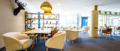 Un interior moderno con comedor, asientos cómodos y elementos decorativos como una cabeza de venado montada y una lámpara colgante.