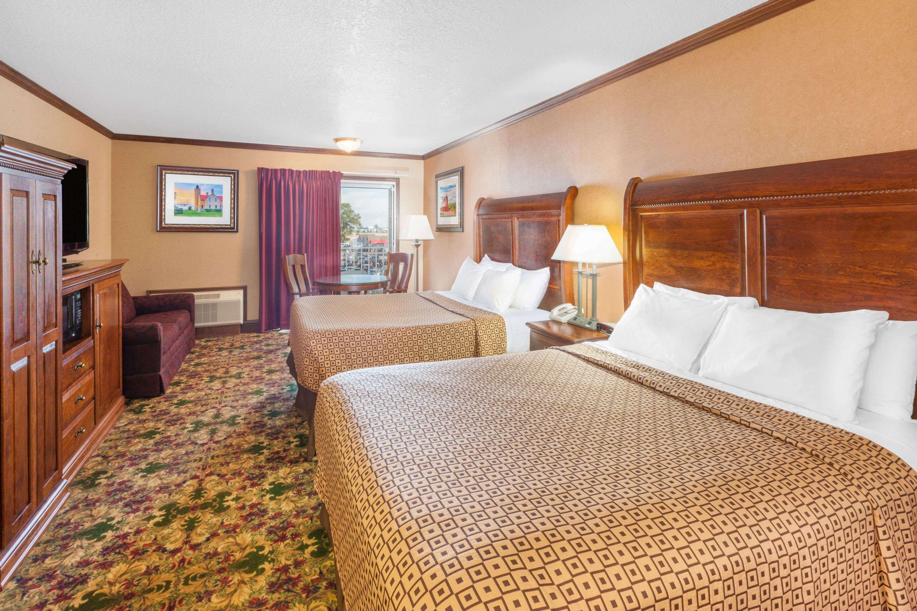 A hotel room with two beds, a desk, a chair, a television, and a window with curtains.