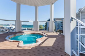 A covered outdoor swimming pool with a view of the sea and a parking area in the background. - Ramada by Wyndham Mackinaw City Waterfront (Mackinaw City)