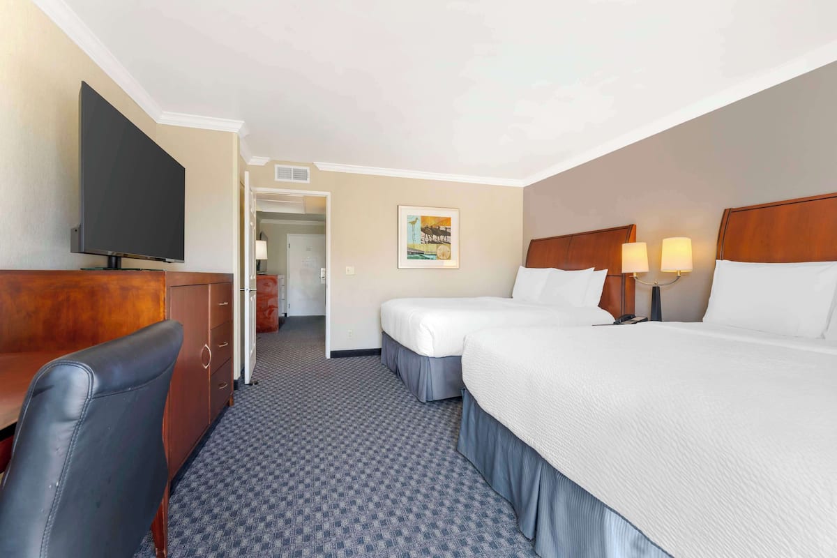 A hotel room with a bed, a desk with a TV, and a chair.