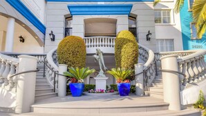 A grand entrance with a white balustrade, a blue overhang, and a statue of dolphins. - Best Western Plus Marina Shores Hotel (Dana Point)