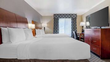 A hotel room with two beds, a desk, a TV, and a wardrobe.