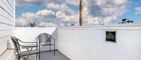 A balcony with two metal chairs, a white wall, and a 'No Smoking' sign.