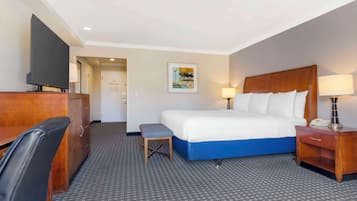 Une chambre d’hôtel avec un lit, un bureau, une chaise, une télévision et un tableau au mur.