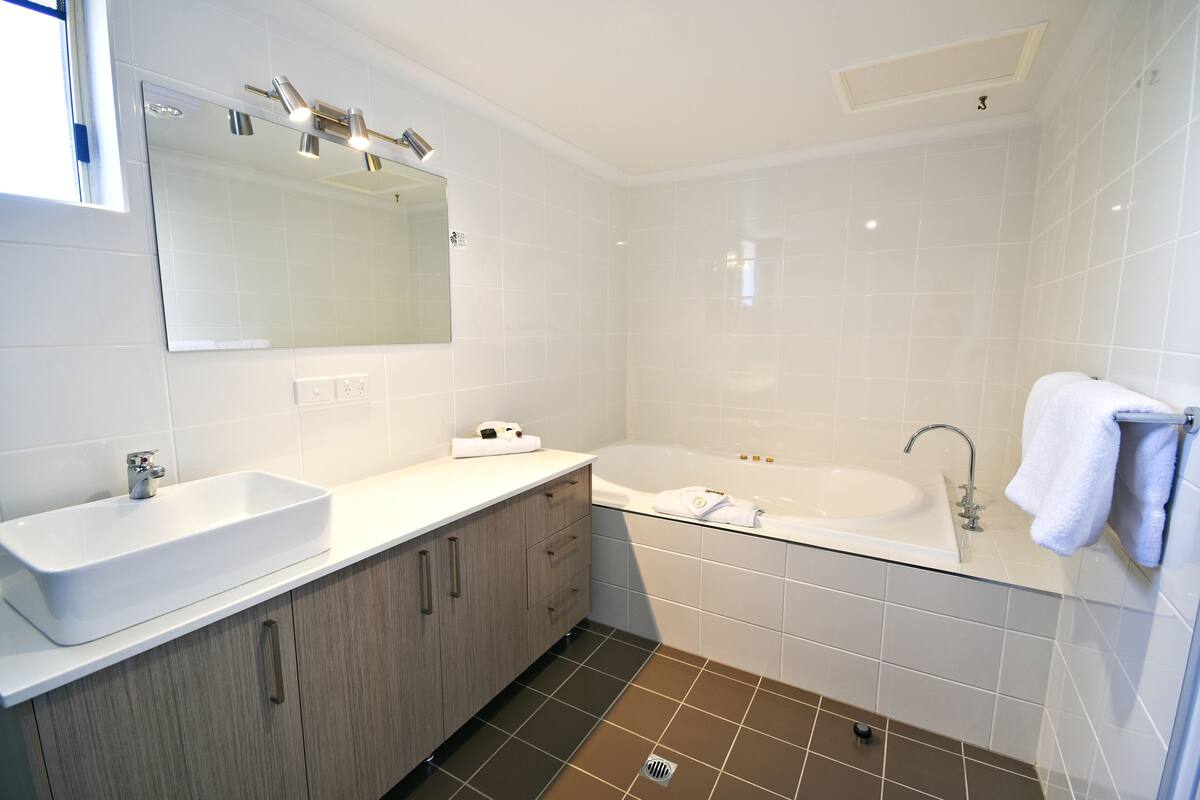 A modern bathroom with a large sink, a bathtub, and a mirror.