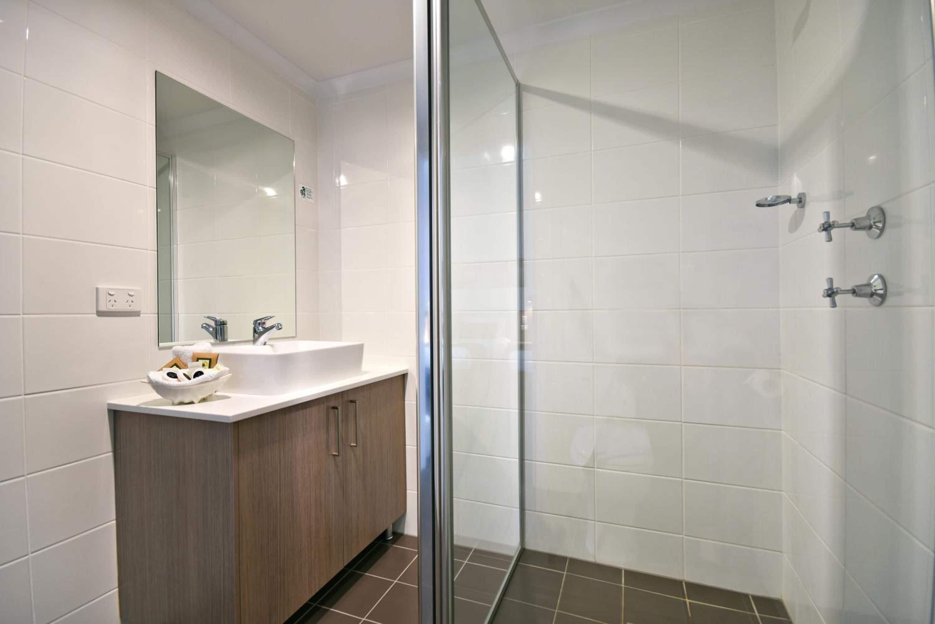 Un baño moderno con cabina de ducha de vidrio, tocador con lavabo y espejo.