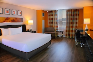 Una habitación de hotel con una cama grande, un escritorio, una silla y una mesita.
