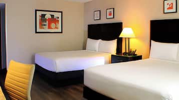 A hotel room with two beds, a chair, and a nightstand with a lamp.