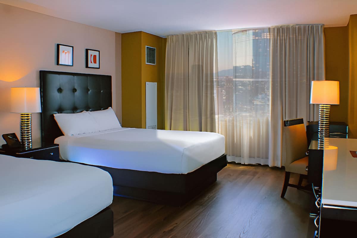 Ein Hotelzimmer mit einem großen Bett, zwei Nachttischen, einem Schreibtisch und einem Sessel.