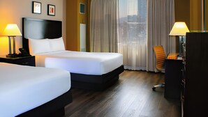 A hotel room with two beds, a desk, a chair, and a large window with curtains. - Circus Circus Hotel, Casino & Theme Park (Las Vegas)