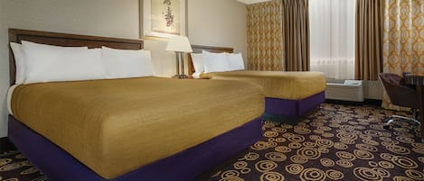 A hotel room with two beds, a desk, and a chair.