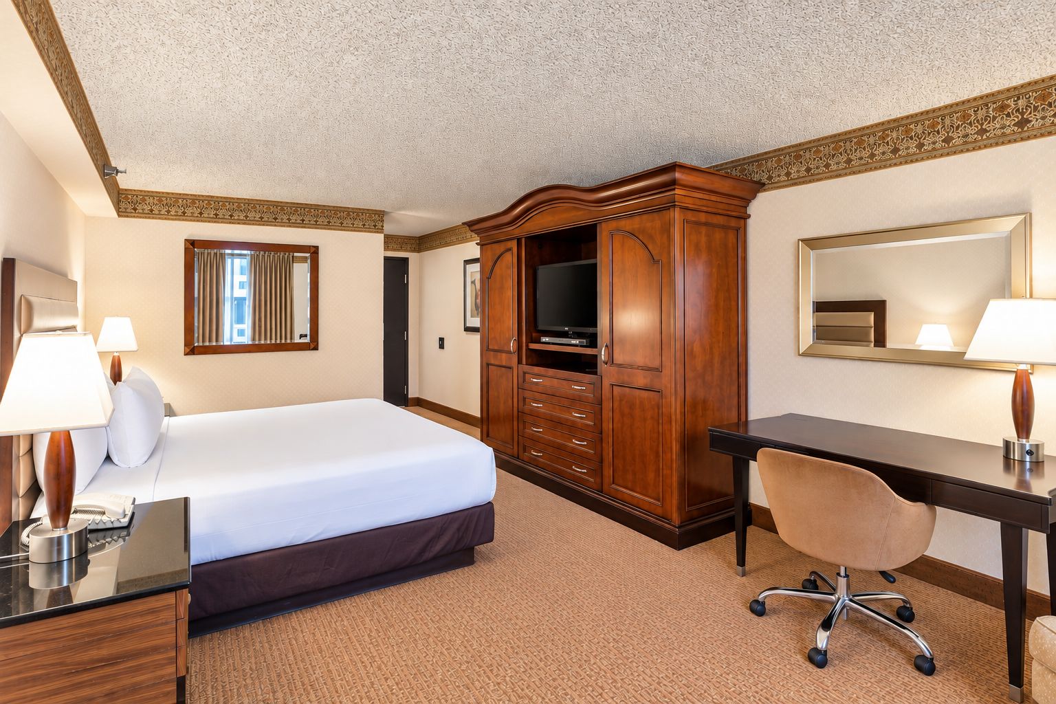 Een hotelkamer met een bed, een bureau, een televisie en een kledingkast.