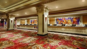 A spacious lobby with ornate columns, a patterned carpet, and a reception desk with a colorful mural. - Circus Circus Hotel, Casino & Theme Park (Las Vegas)