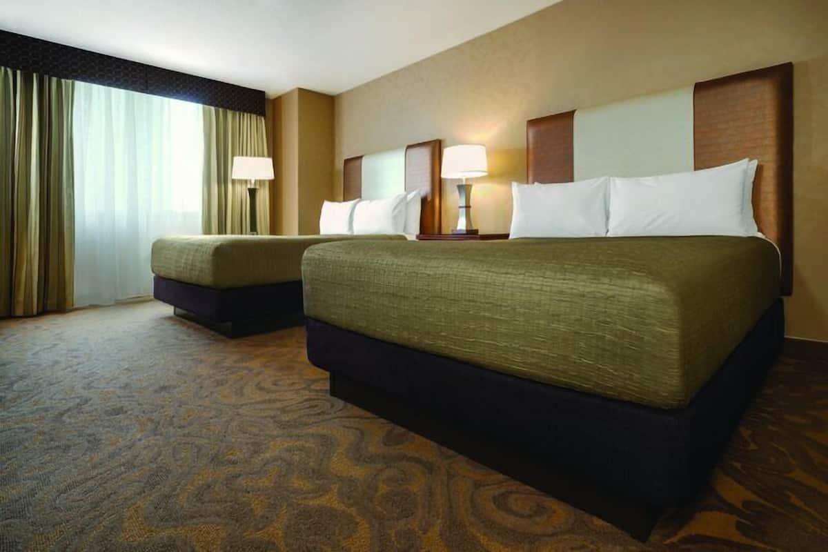 Ein Hotelzimmer mit zwei Betten, Teppichboden und einem Vorhangfenster.