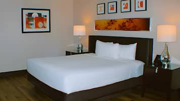 Ein Hotelzimmer mit einem großen Bett, zwei Nachttischen inklusive Lampen und Bildern an den Wänden.