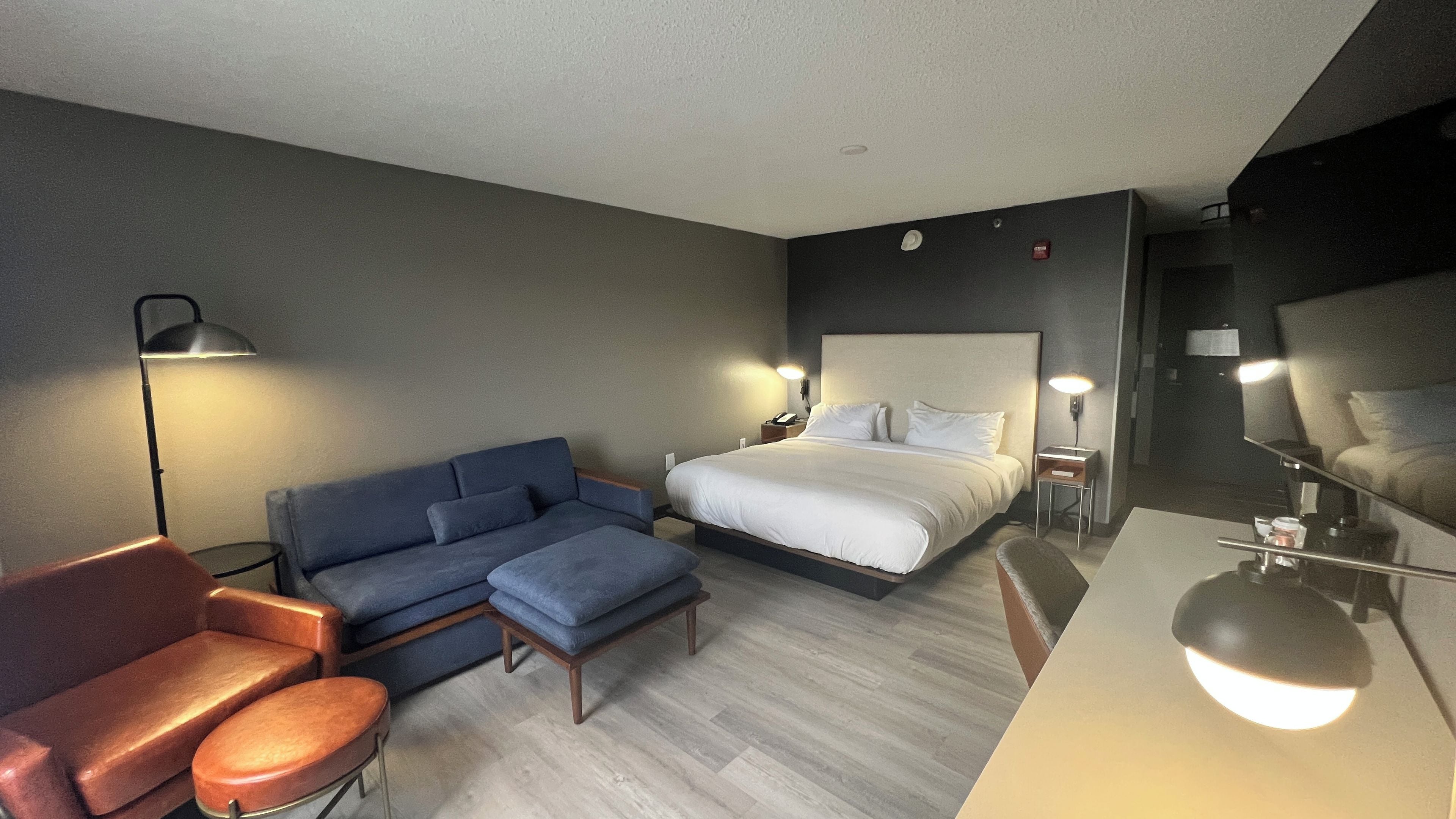 Una habitación de hotel con una cama, un sofá, una silla, un escritorio y una lámpara.