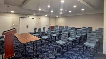Een vergaderzaal met rijen stoelen, een spreekgestoelte en een vloerbedekking.