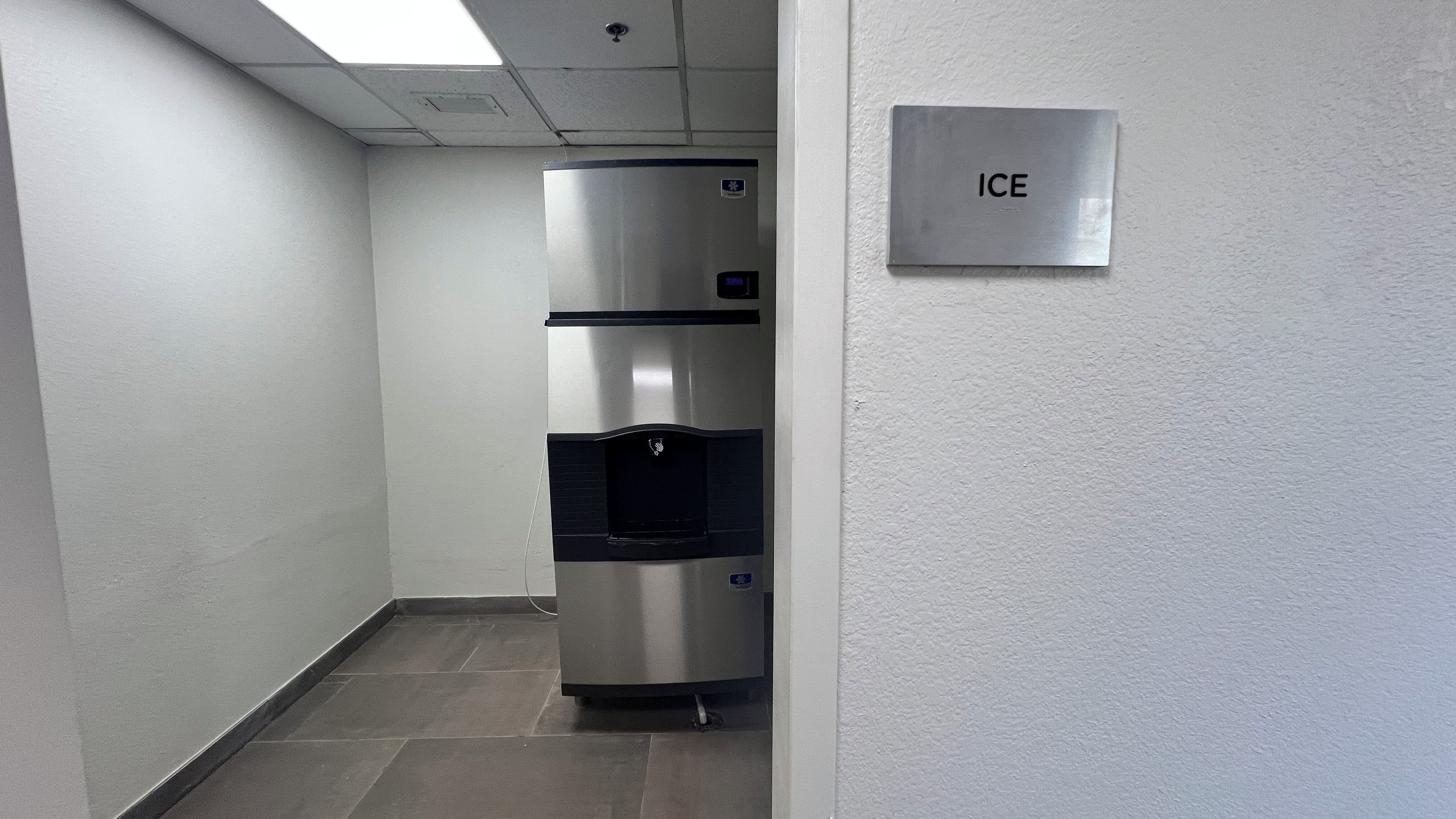 Un pasillo con un refrigerador de acero inoxidable y un dispensador de hielo en la pared.