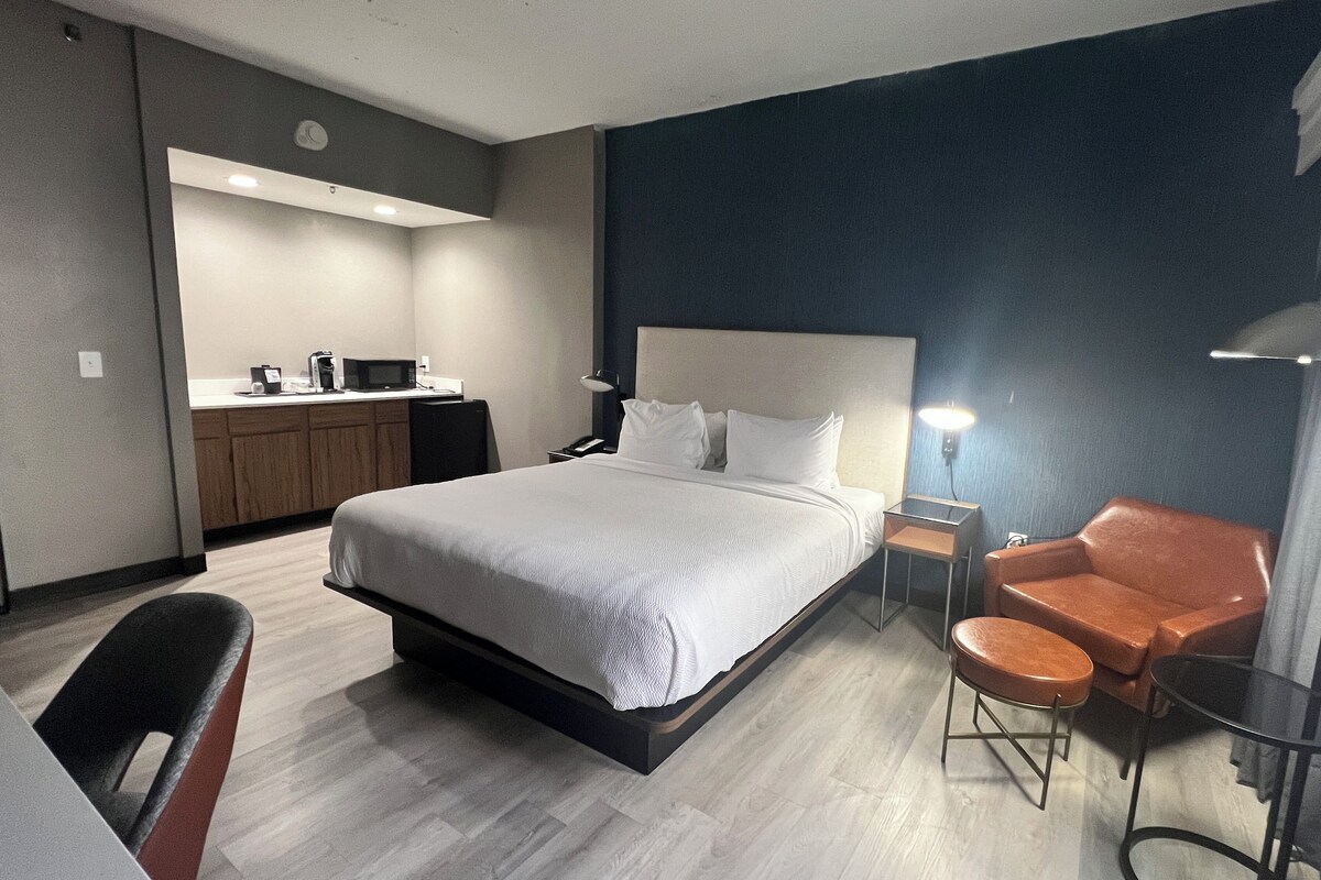 Een hotelkamer met een bed, een bureau, een stoel, een bank en een kitchenette.