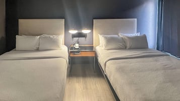 Ein Hotelzimmer mit zwei Betten, einem Nachttisch mit Telefon und einer wandmontierten Lampe.