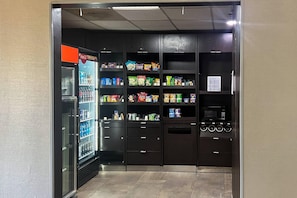 Ein Automatenbereich mit Snacks, Getränken und einer Mikrowelle.